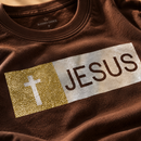 Detalhe do aplique glitter dourado cruz e JESUS na camiseta marrom